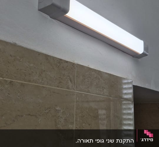 מנורת פלורסנט מותקנת על קיר בחדר אמבטיה